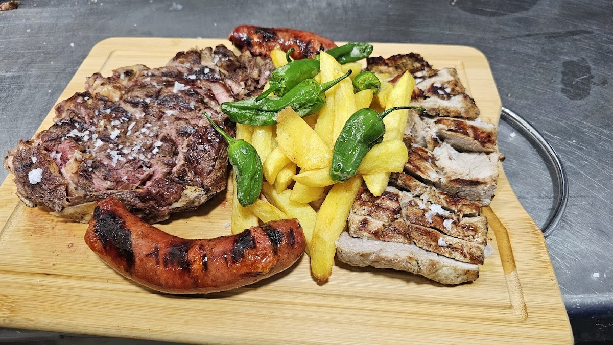 Plato de carne asada con chorizo, patatas fritas y pimientos verdes