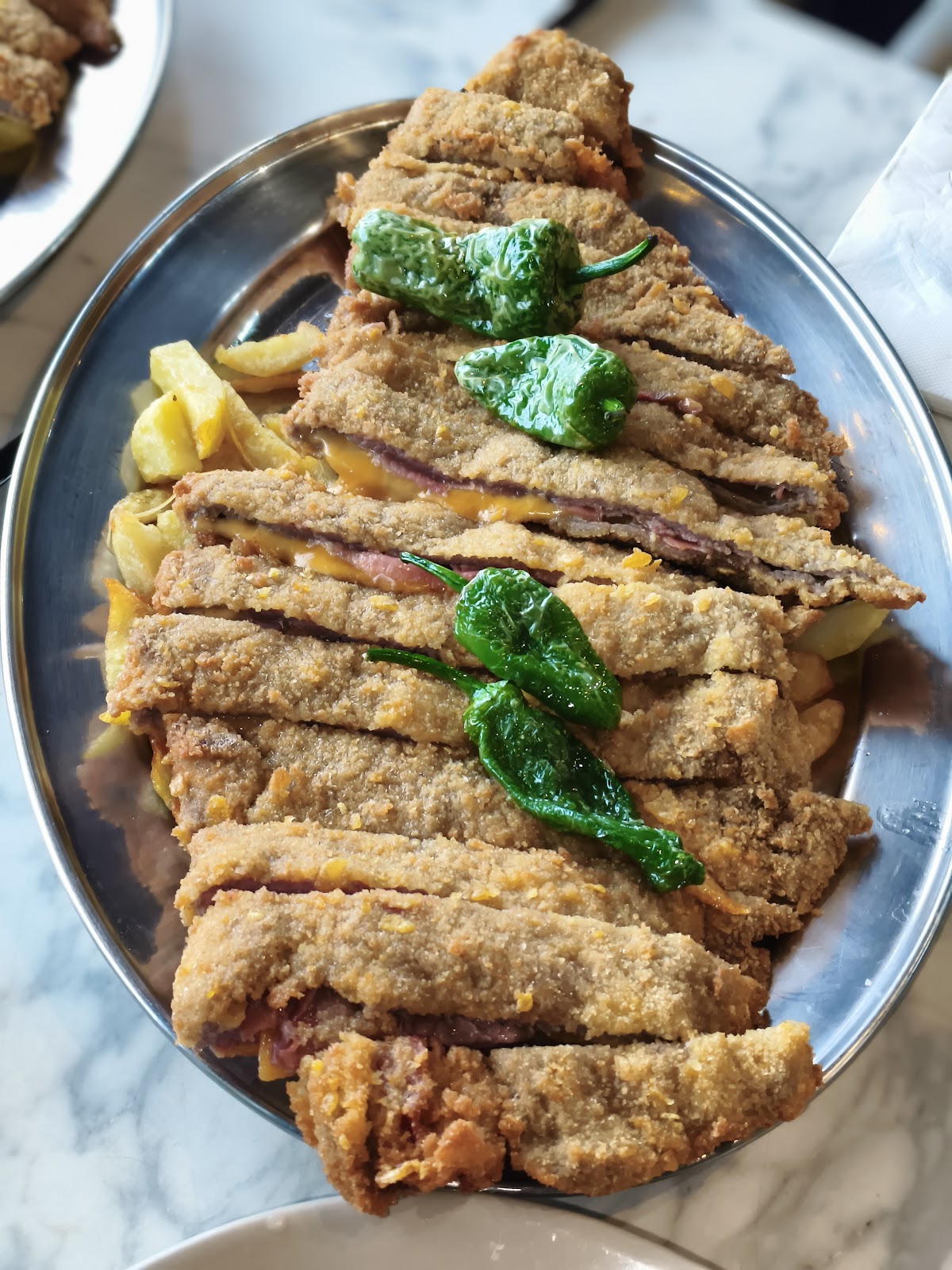 Filete empanizado servido con patatas fritas y pimientos verdes